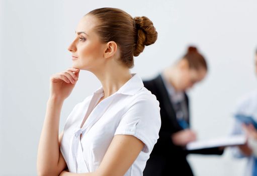 Attractive businesswoman looking thoughtfully with colleagues at background