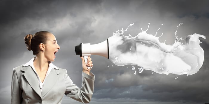 businesswoman in grey suit screaming into megaphone