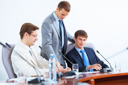 Image of three businesspeople at table at conference