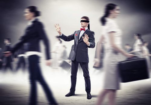 Image of businessman in blindfold walking among group of people