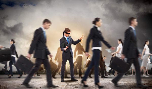 Image of businessman in blindfold walking among group of people