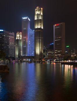 Singapore quay with tall illuminated skyscrapers in the central business district at night