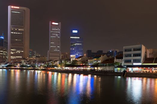 Singapore quay at night with tall skyscrapers in the central business district and and small restaurants on Boat Quay 