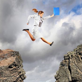 Image of young businesswoman jumping over gap