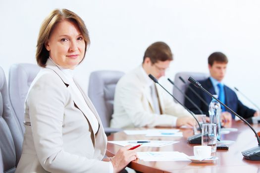 Image of three businesspeople sitting at table at conference