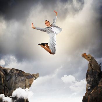 Image of young businesswoman jumping over gap