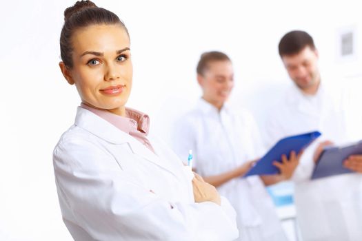 Young female doctor in white uniform with collegues on the background