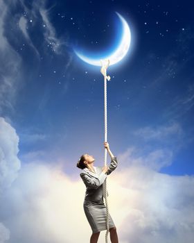 Image of businesswoman climbing the rope to the moon