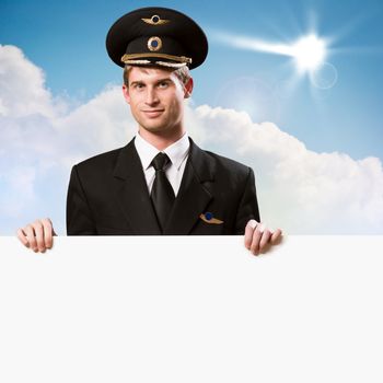 pilot in the form of holding an empty billboard on the background of sky with clouds, place for text