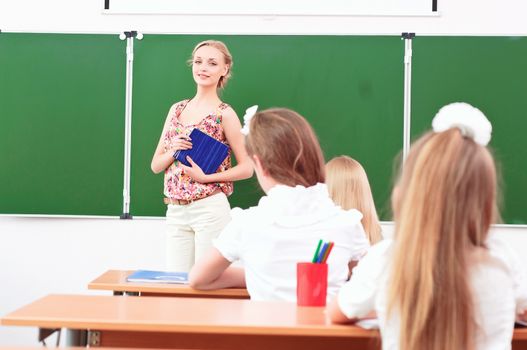 teacher stands in front of students in the class