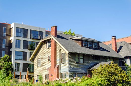 Old dilapidated house in a neighborhood with nice stylish apartments in Portland, Oregon