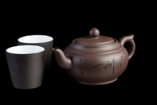 Chinese teapot with teacup on black background