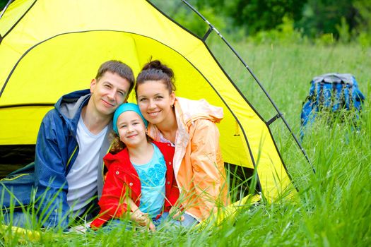Summer vacation. Family of three in tent in camping on the nature.