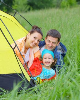 Summer vacation. Family of three in tent in camping on the nature. Vertical view