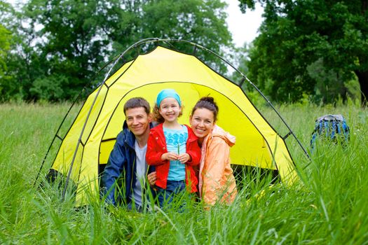 Summer vacation. Family of three in tent in camping on the nature.