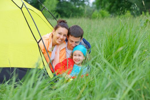 Summer vacation. Family of three in tent in camping on the nature.