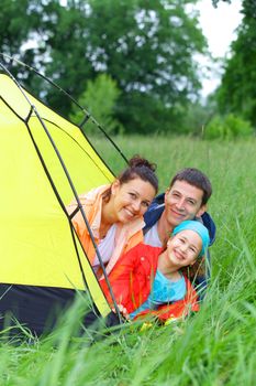 Summer vacation. Family of three in tent in camping on the nature. Vertical view