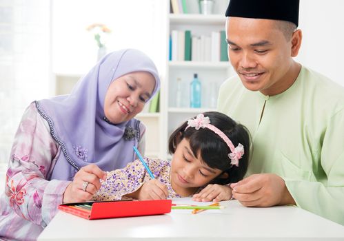 Muslim family drawing and painting picture at home. Southeast Asian family lifestyle. Happy smiling parents and child.