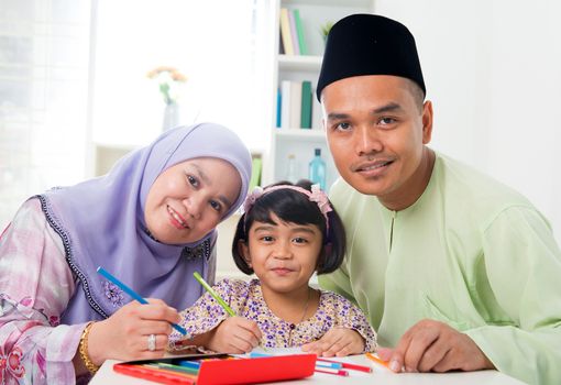 Southeast Asian family drawing and painting picture at home. Malay Muslim family lifestyle. Happy smiling parents and child.