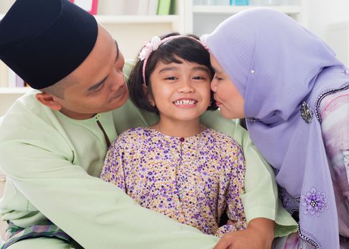 Muslim parents kissing child. Southeast Asian Malay family lifestyle. Happy smiling father mother and daughter.