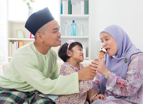 Feeding ice cream. Muslim girl feeding mother an ice cream. Beautiful Southeast Asian family living lifestyle at home.