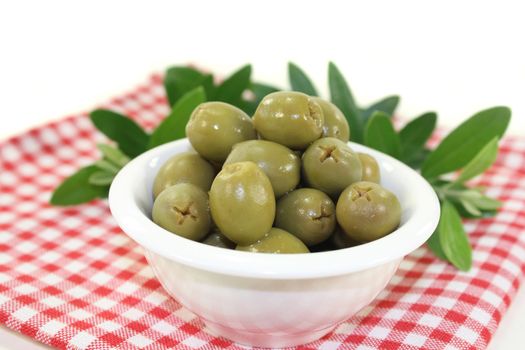 green olives and olive branch in a white bowl