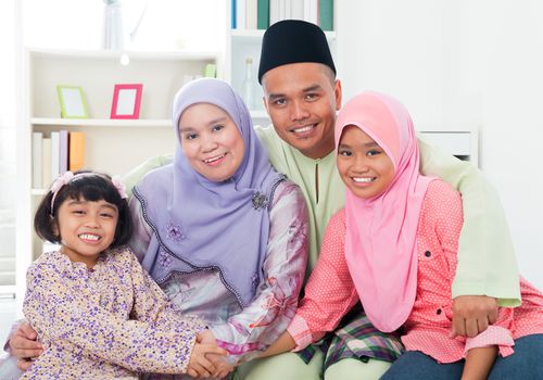 Happy Asian family at home. Muslim family having fun indoors. Southeast Asian parents and children smiling.
