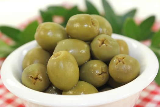 green olives and olive branch in a white bowl