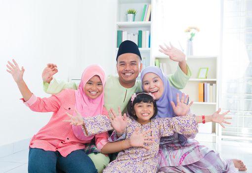 Happy Asian family at home. Muslim family having fun. Southeast Asian parents and children open arms smiling.