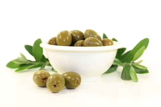 green olives and olive branch in a white bowl