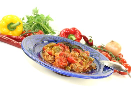 Tagine Kefta with tomatoes, peppers and ground beef on a bright background