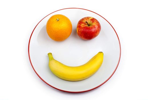 Three different pieces of fruit making up a smiling face on a plate over a white background.