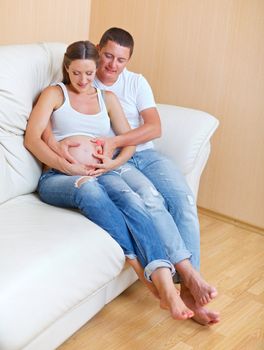 Couple sitting near on the sofa and smiling and pending the kid