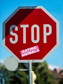 stop roadsign decorated with additional sticker: eating animals