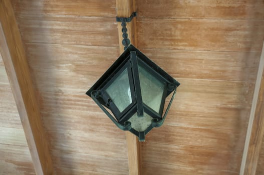 old lamp hanging from the ceiling of a porch