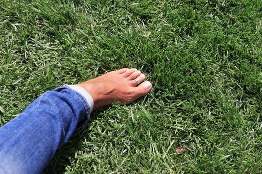 Bare feet in green grass, woman relaxing in nature