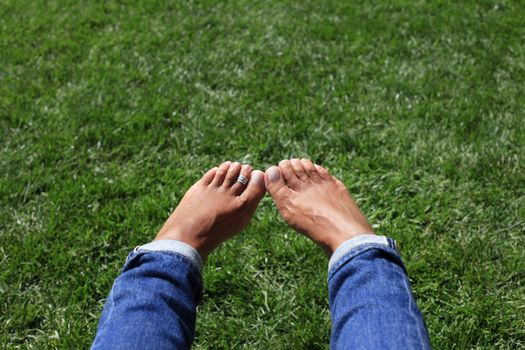Bare feet in green grass, woman relaxing in nature