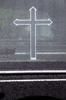 part of hearse window covered in raindrops with cross