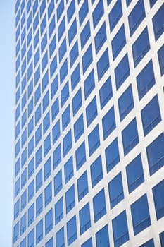 modern office building reflecting blue sky in many square windows
