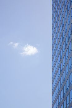stern facade of office building and one cloud in blue sky