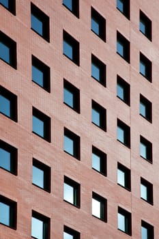 brick facade of office building with many windows reflecting blue sky