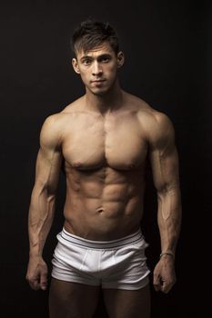 Portrait of muscular young man over black background