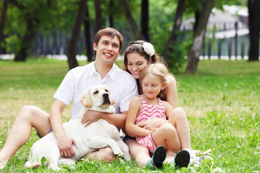 Young Family Outdoors in summer park with a dog