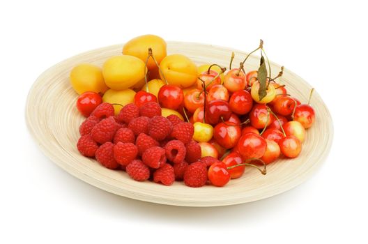 Arrangement of Juicy Apricots, Sweet Cherries and Raspberries on Wooden Plate isolated on white background