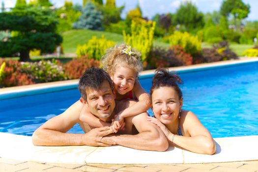 Pretty little girl with her parent in swimming pool outdoors