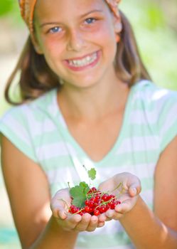 Young girl holding in hand organic natural healthy food produce - red currant. Focus on the red currant. Vertical view