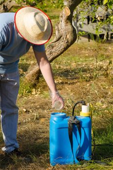 Agricultural worker filling a  sprayer with pesticide