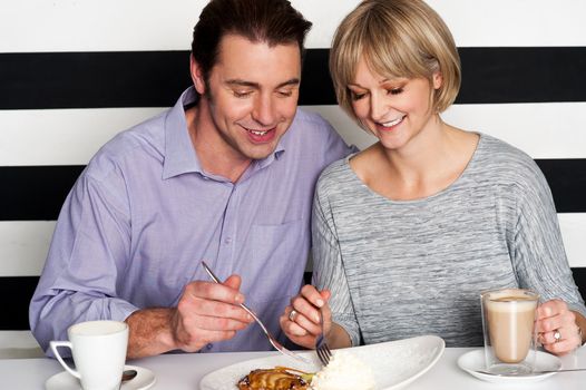 Beautiful middle aged couple enjoying coffee and trying new cuisine