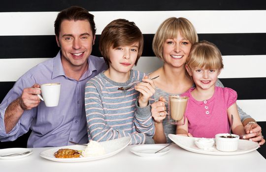 Happy family of four enjoying breakfast at a restaurant