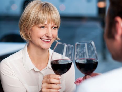 Gorgeous middle aged woman looking at her man with love and toasting wine